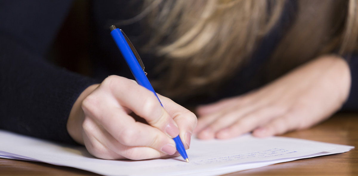 Close-up image of a student writing on a piece of paper