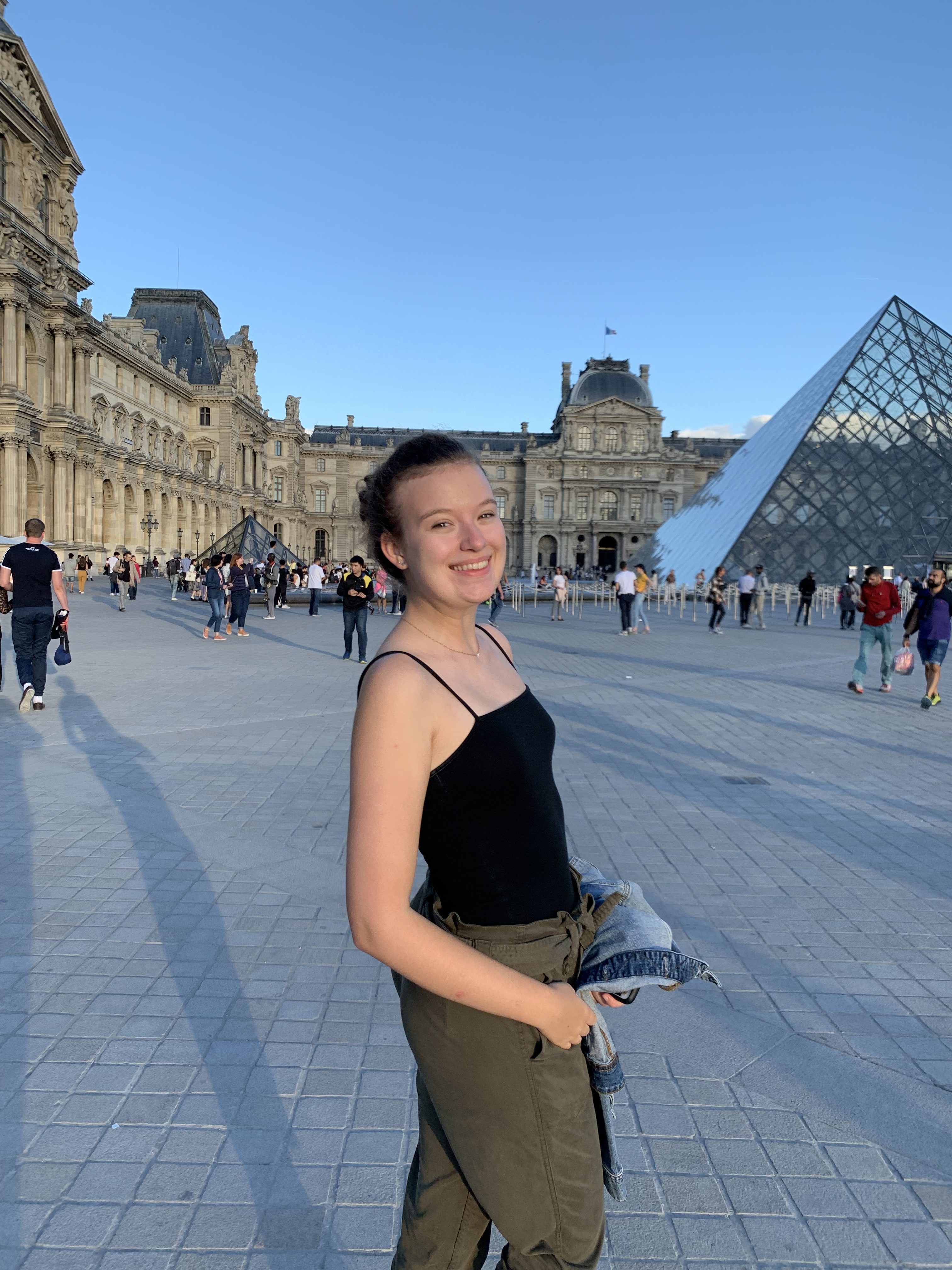 Female student in front of pyramid at the louvre in Paris.