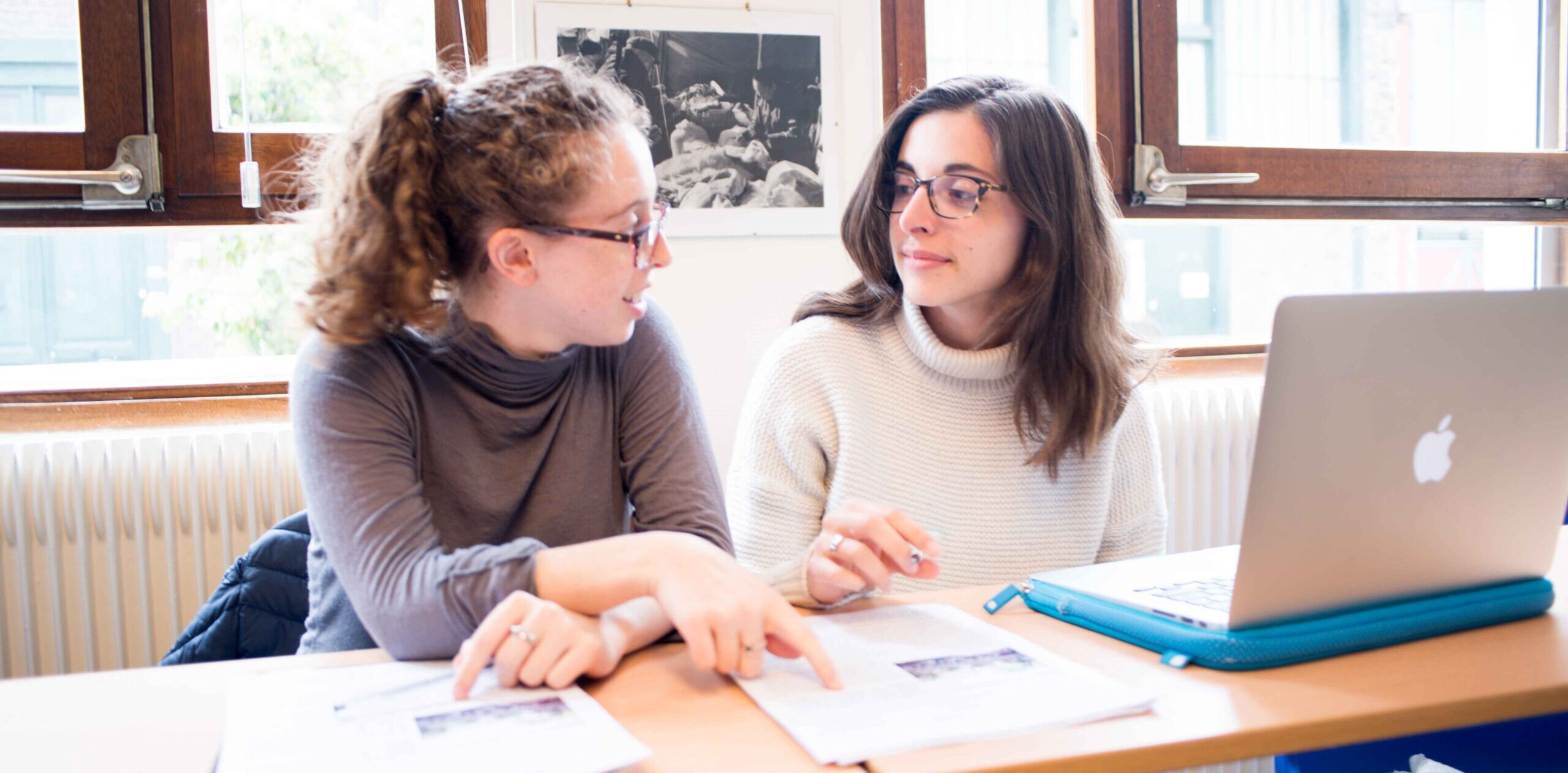 two female students working at a desk with a computer in Paris during study abroad.