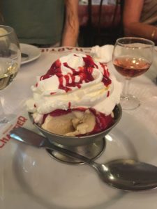 Dish of ice cream with whipped cream and raspberry sauce