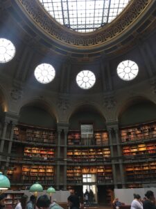 High-ceilinged oval room lined with bookshelves, with round windows and a skylight