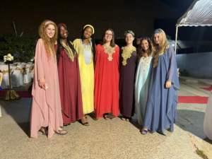 A group of smiling young women wearing long dresses in different colors