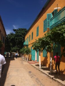 Narrow street with a bright yellow building with teal accents