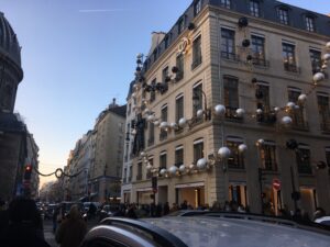 A street in Paris with a building covered in enormous Christmas garlands
